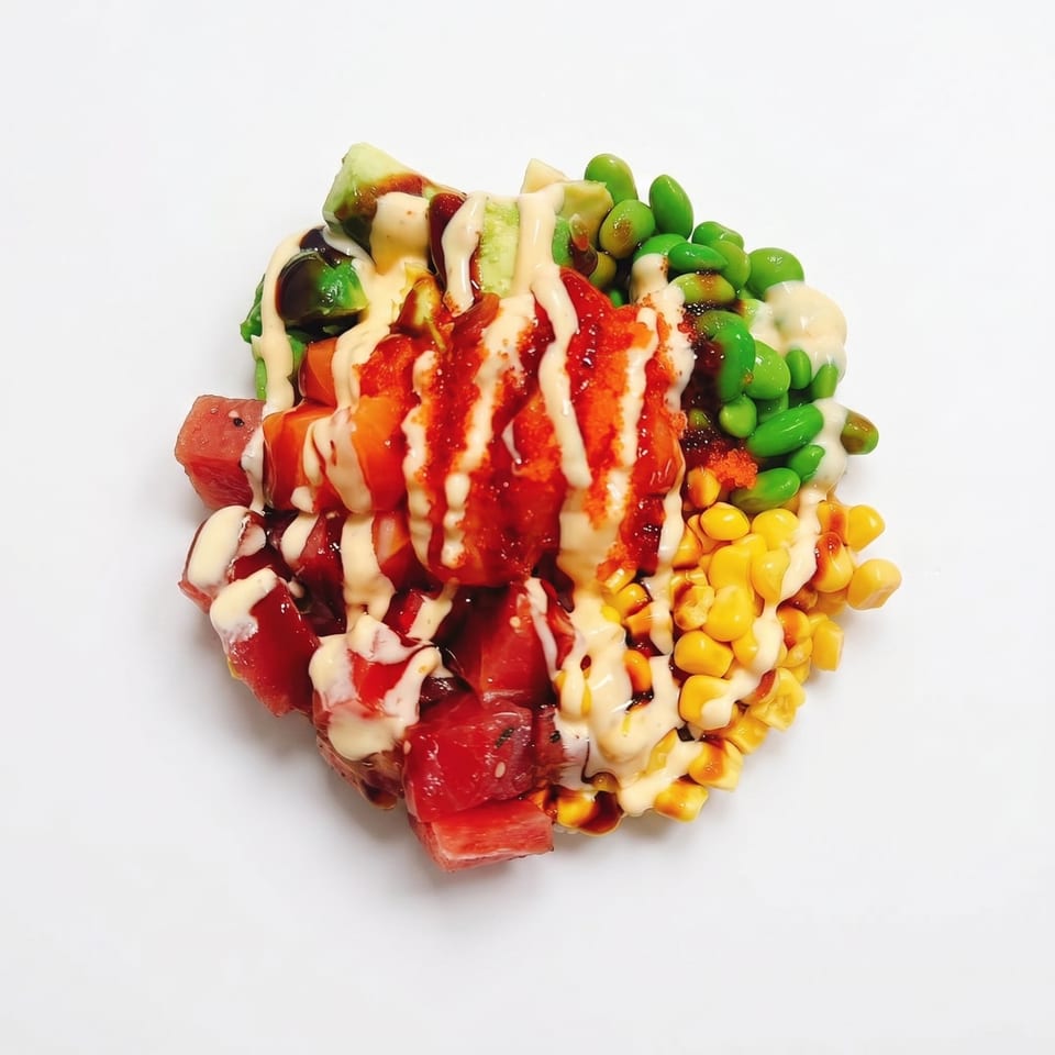 Colorful poke bowl with tuna, salmon, avocado, edamame, and corn, drizzled with sauces.